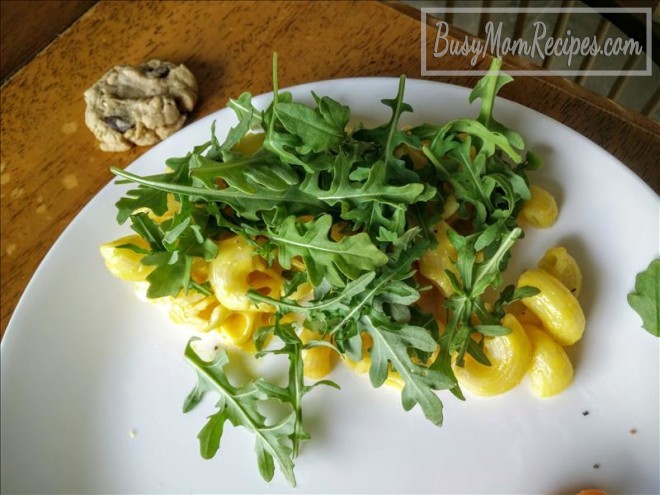 homemade mac and cheese on the stove with arugula